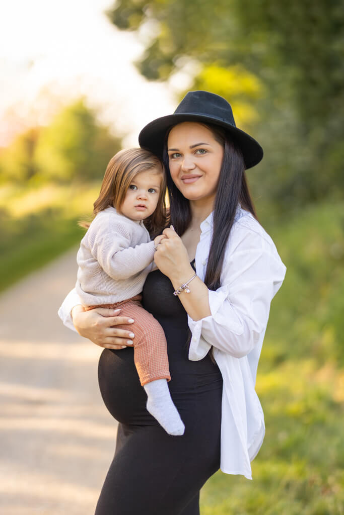 Mama und Kind stehen bei einem Babybauchshooting gemeinsam vor der Kamera an einem See in Bremen.